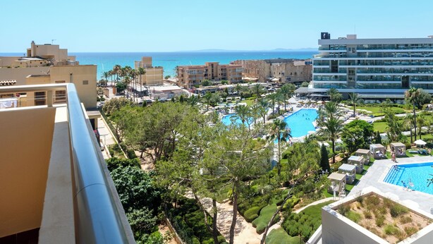 Un resort con piscina, palmeras y vistas al mar.