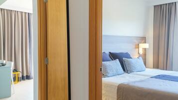 A hotel room with a bed, a bedside table, and a mirror reflecting the room.