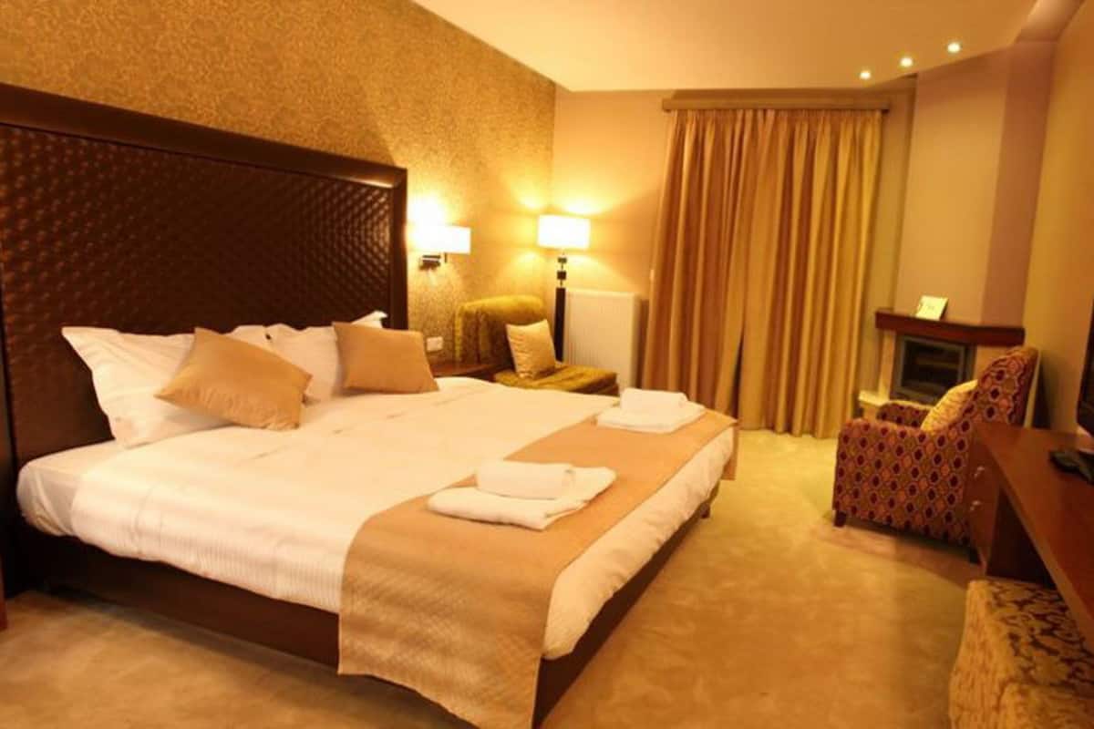 Une chambre d’hôtel avec un grand lit, un bureau avec une chaise, une télévision et une cheminée.