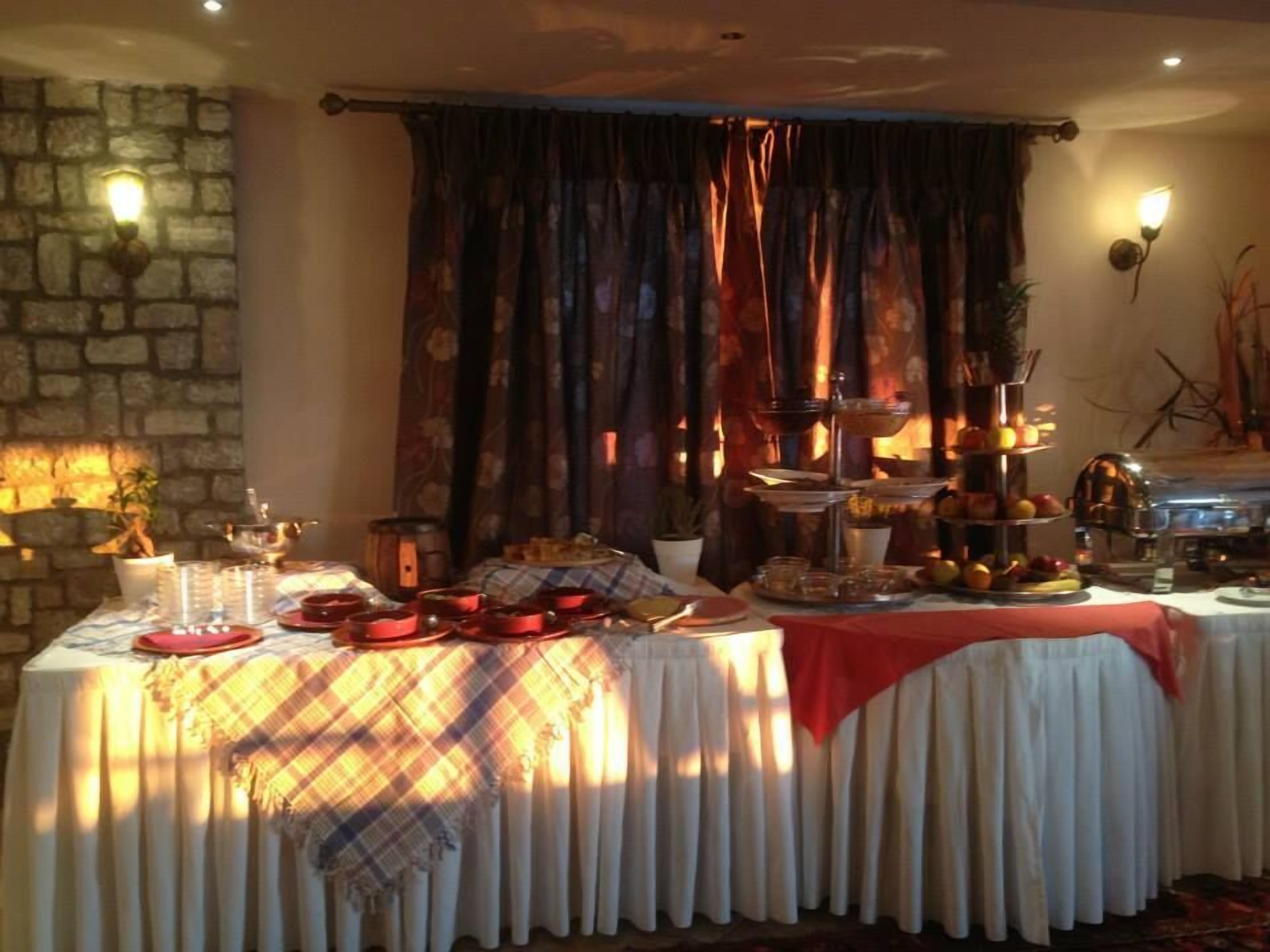 Un'area pranzo con parete in pietra, camino e tavolo apparecchiato con diversi piatti e bicchieri.