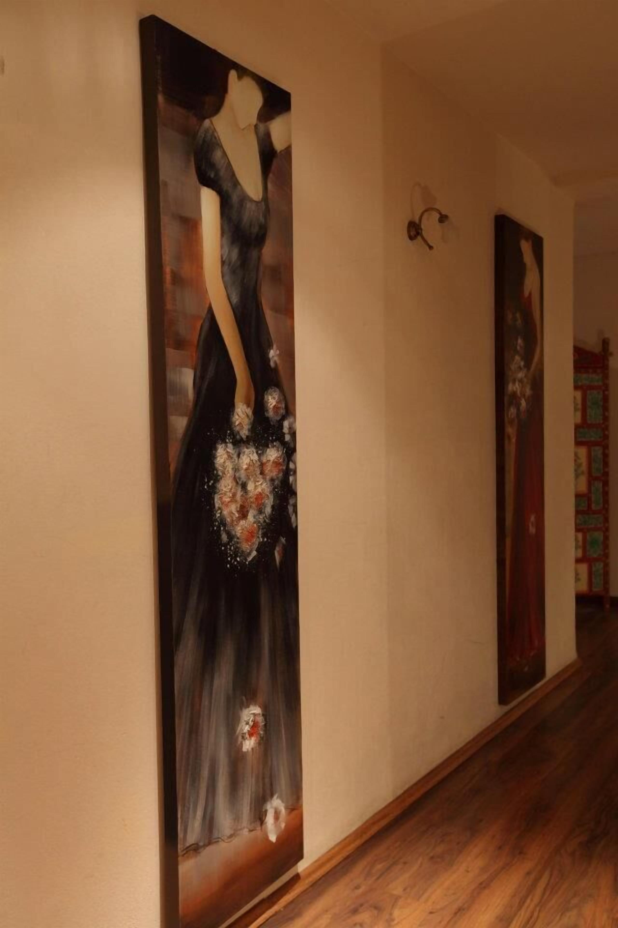 A hallway with a painting of a woman in a dress and a bookshelf in the background.