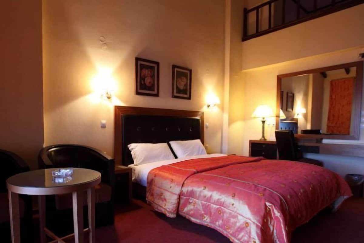Une chambre d’hôtel comprenant un lit, un bureau, deux chaises, une petite table et un miroir.