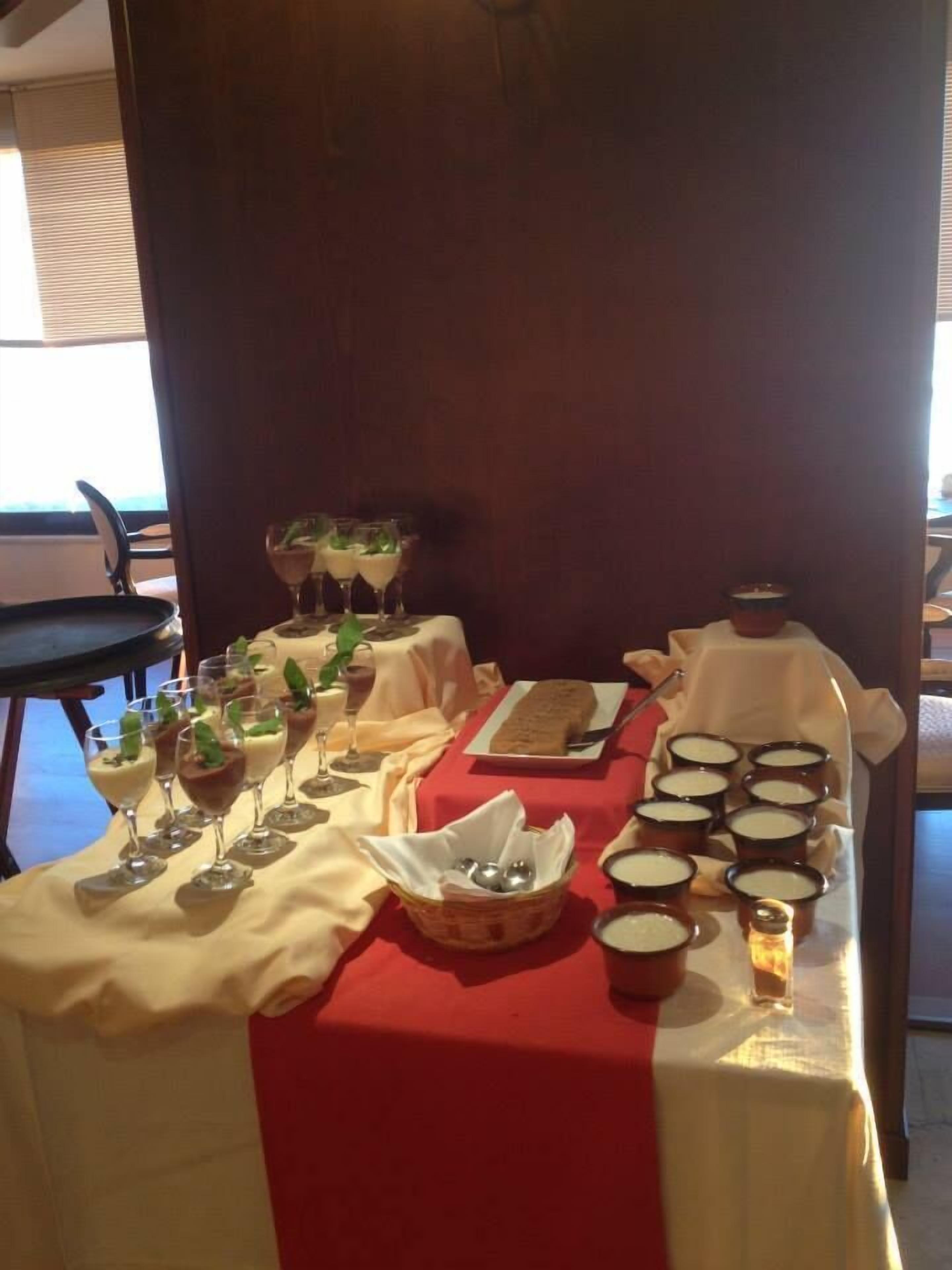 Een eettafel gedekt met diverse gerechten en drankjes, waaronder een brood en meerdere kommen soep.