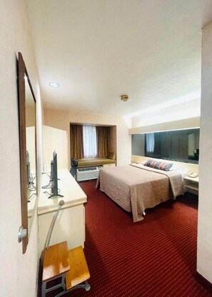 A hotel room with a bed, a desk with a computer, a mirror, and a window with curtains. - Metrotel Express (San Pedro Sula)