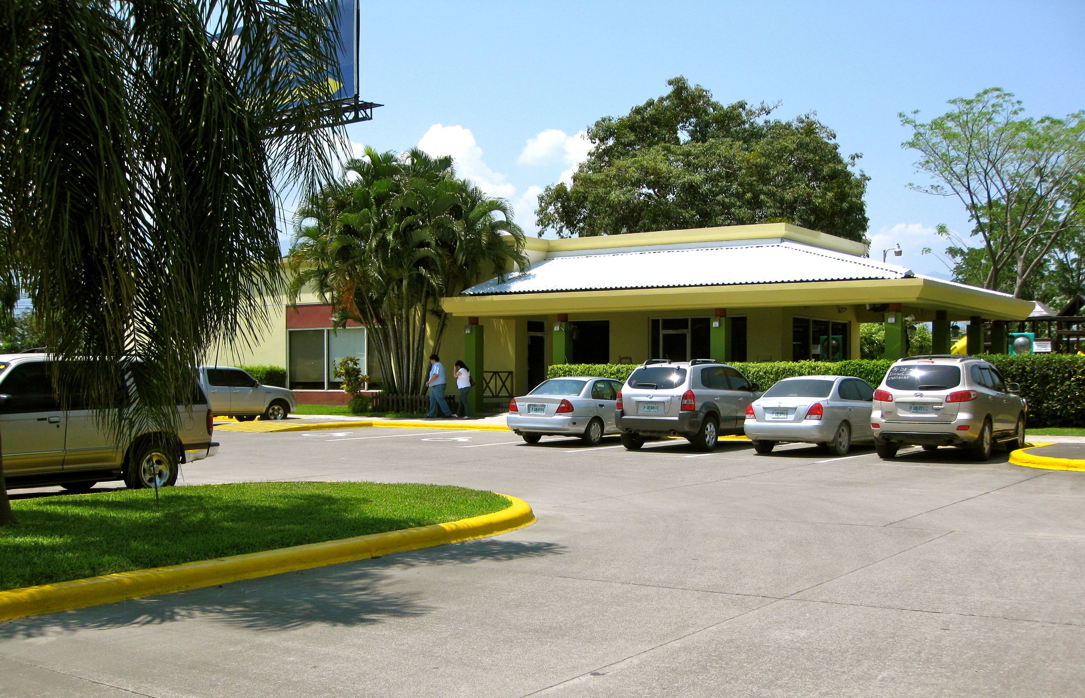 A parking lot with several cars and a building with a yellow roof.