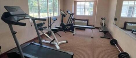 A gym with treadmills, elliptical machines, and a weight bench.
