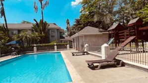 A swimming pool with lounge chairs and a covered area. - Metrotel Express (San Pedro Sula)