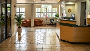 A hotel lobby with a reception desk, seating area, and large windows allowing natural light. - Metrotel Express (San Pedro Sula)