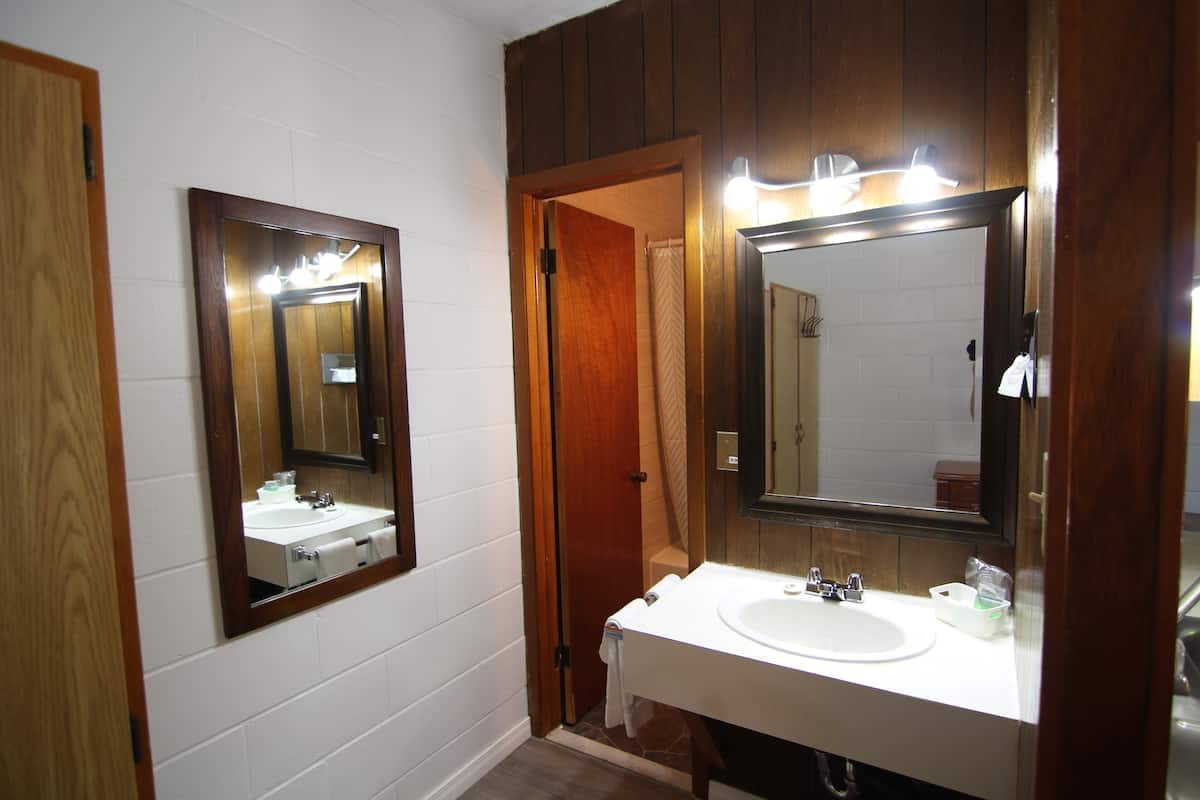 Un baño con un lavamanos blanco, un espejo y paneles de madera en las paredes.
