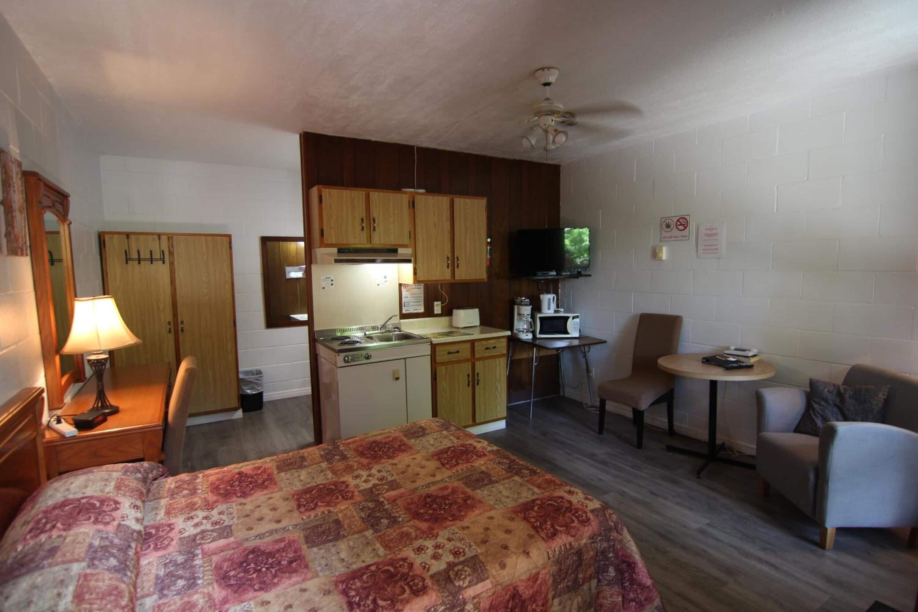 Une chambre d’hôtel compacte comprenant un lit, une kitchenette et un coin salon.