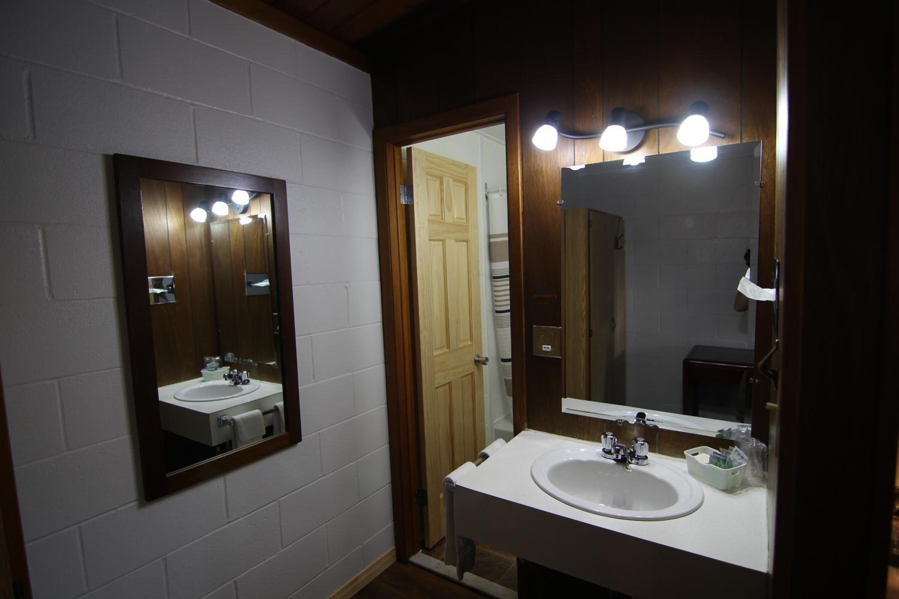 A bathroom with a white sink, a mirror, and a wooden door.