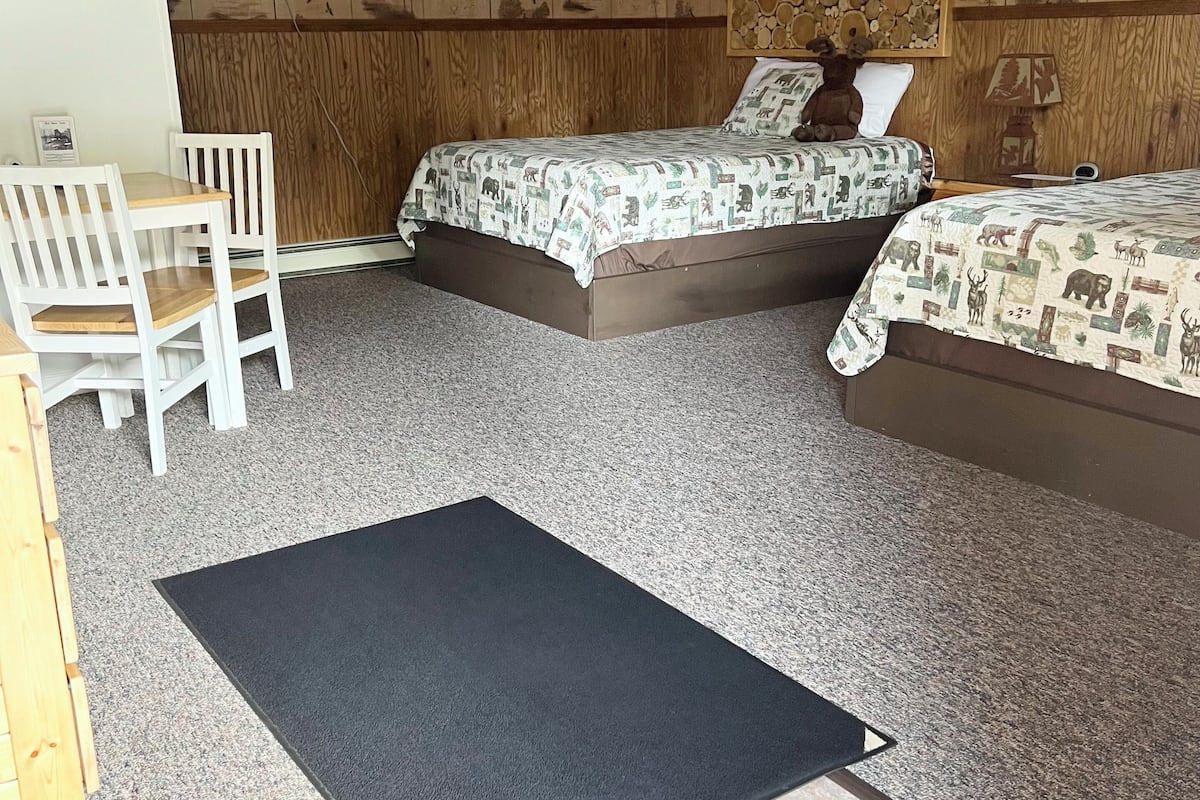 A bedroom with two beds, a desk, and a chair.