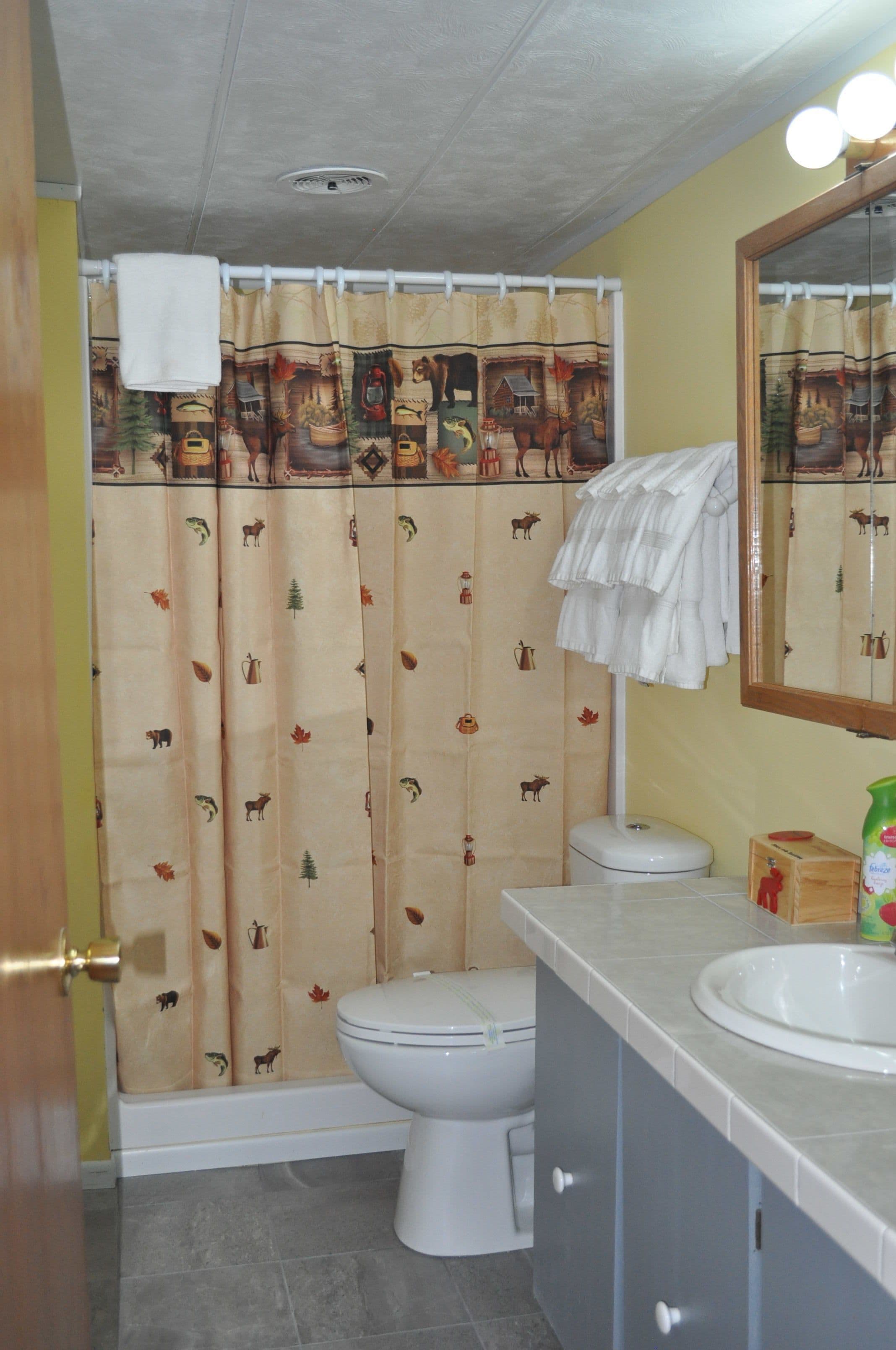 A bathroom with a toilet, sink, and shower curtain with animal prints.