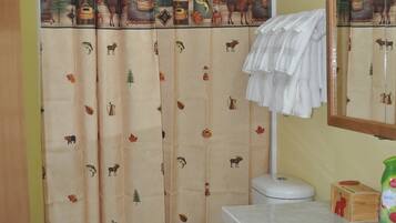 A bathroom with a toilet, sink, and shower curtain with animal prints.