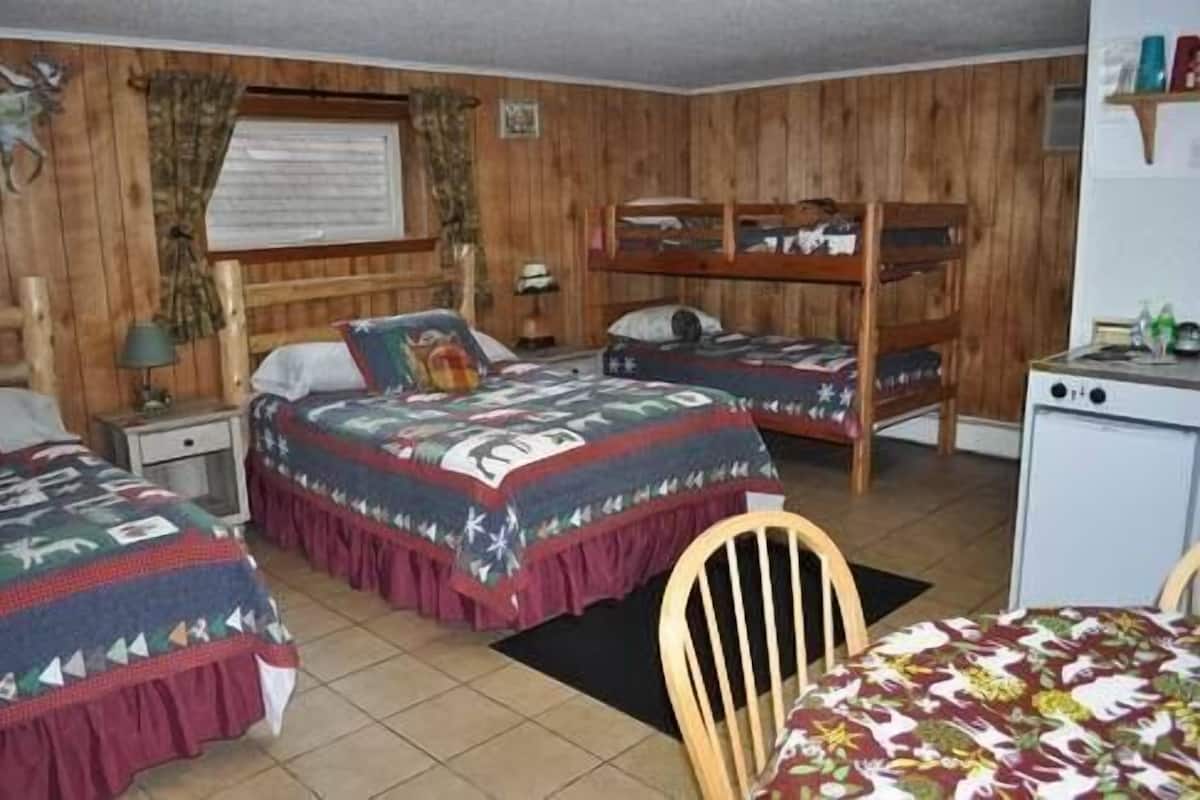 A room with two single beds, a bunk bed, a desk, and a chair.