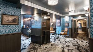 A hotel lobby with patterned wallpaper, a chandelier, and a carpeted floor. - Auberge du Tresor (Québec City)