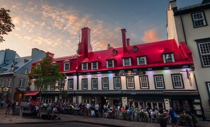 A historic building with a red roof and multiple windows, featuring a restaurant named "Viandos & Vins" on the ground floor. - Auberge du Tresor (Québec City)