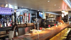 A bar area with a long wooden counter, multiple beer taps, and a variety of bottles. - Auberge du Tresor (Québec City)