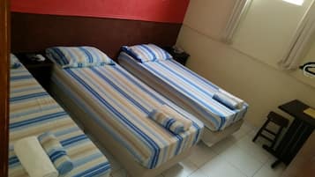 A hotel room with two single beds, a small table, a chair, and a telephone on a nightstand.