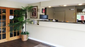 A reception area with a wooden door labeled "STAFF ONLY," a television on a counter, a plant, and a framed picture on the wall.