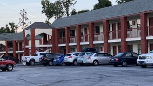 A parking lot with several cars parked in front of a multi-story motel with balconies.