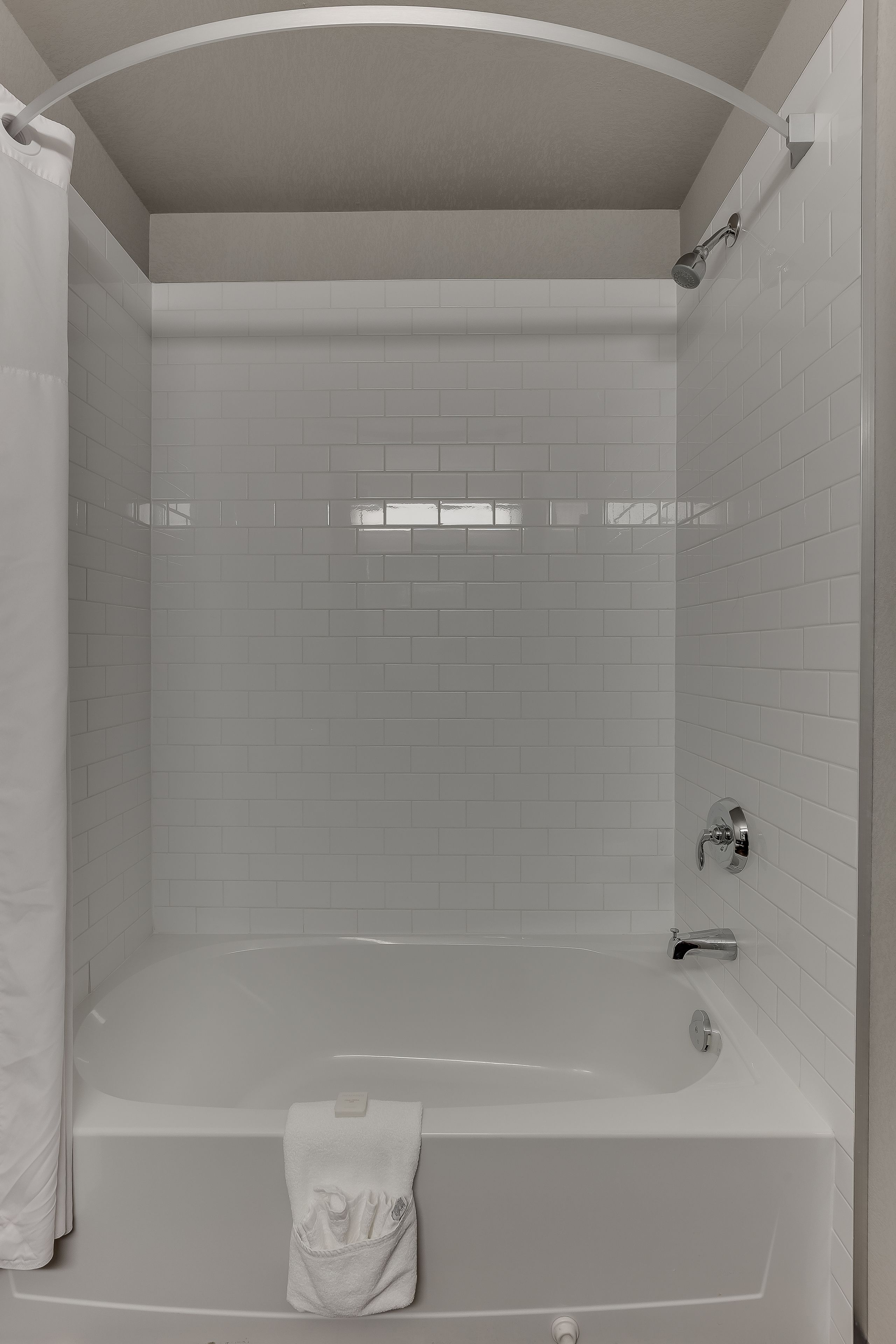 Un baño moderno con una bañera independiente, un cabezal de ducha y un perchero para toallas.