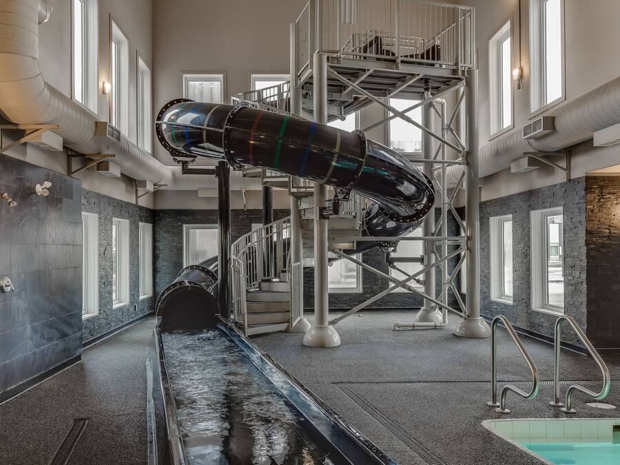 An indoor swimming pool with a diving board and a water slide.