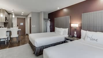 A hotel room with two beds, a desk, and a chair.