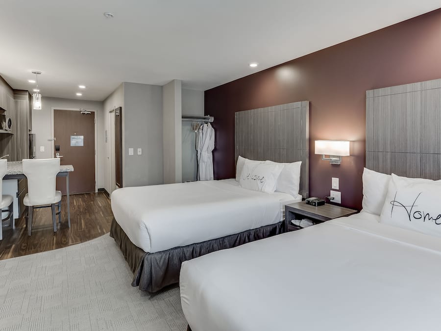 Quarto de hotel com duas camas, uma escrivaninha e uma cadeira.