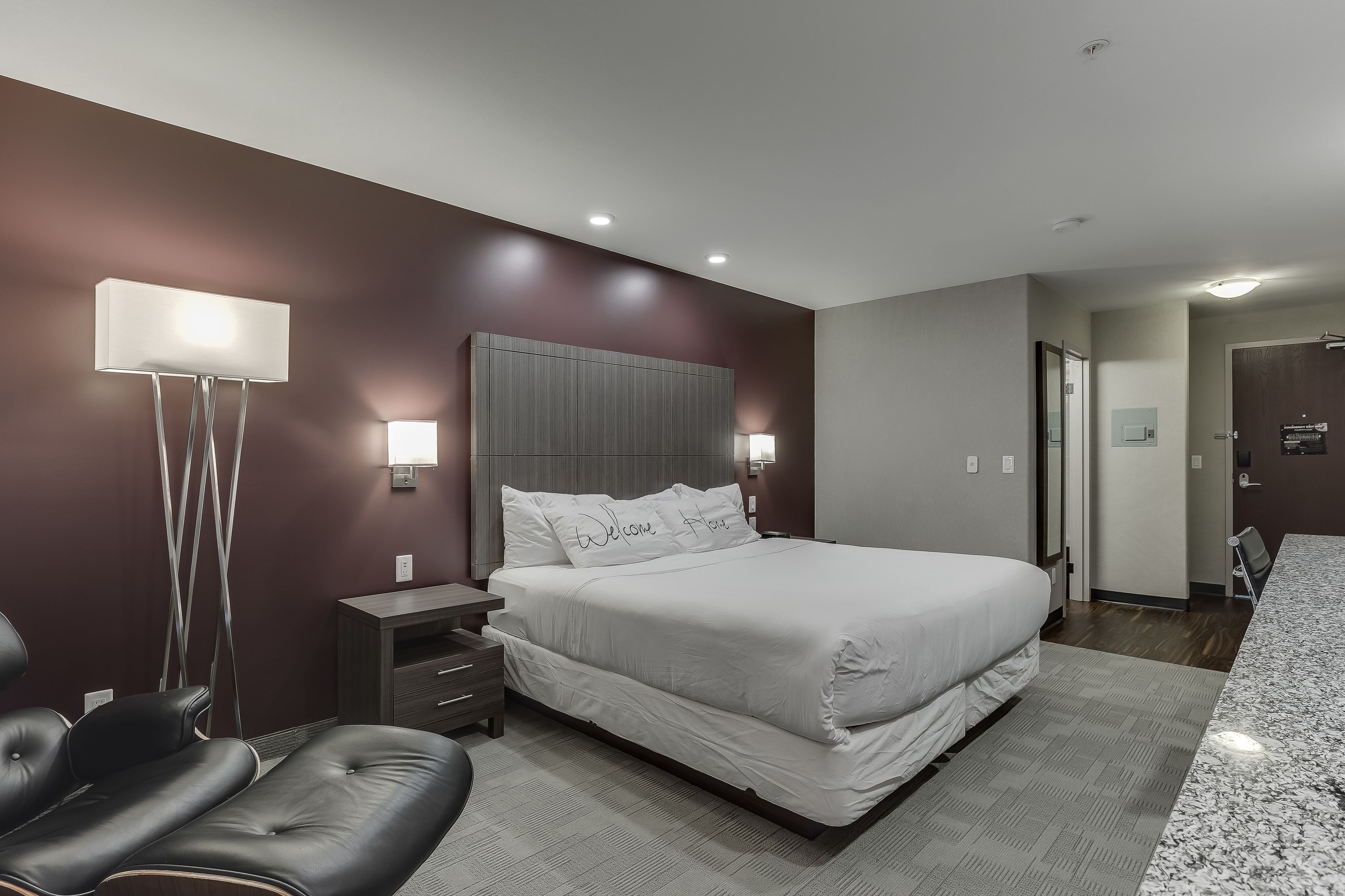 Un dormitorio moderno con una cama grande, mesitas de noche, un escritorio y una silla.