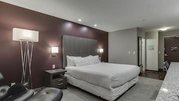 Un dormitorio moderno con una cama grande, mesitas de noche, un escritorio y una silla.