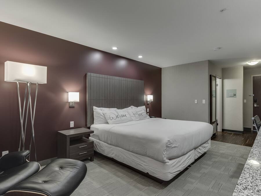 Un dormitorio moderno con una cama grande, mesitas de noche, un escritorio y una silla.