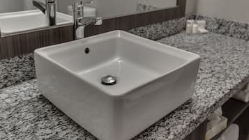 Un bany amb un vàter blanc, un mirall i una superfície de pedra granítica.