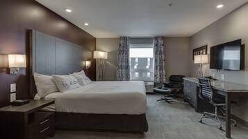 A modern hotel room with a large bed, a desk, and a TV.