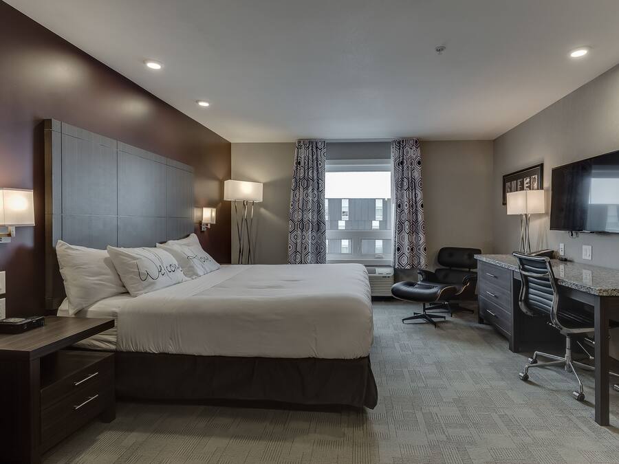 A modern hotel room with a large bed, a desk, and a TV.