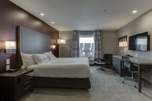 Une chambre d’hôtel moderne avec un grand lit, un bureau et une télévision.