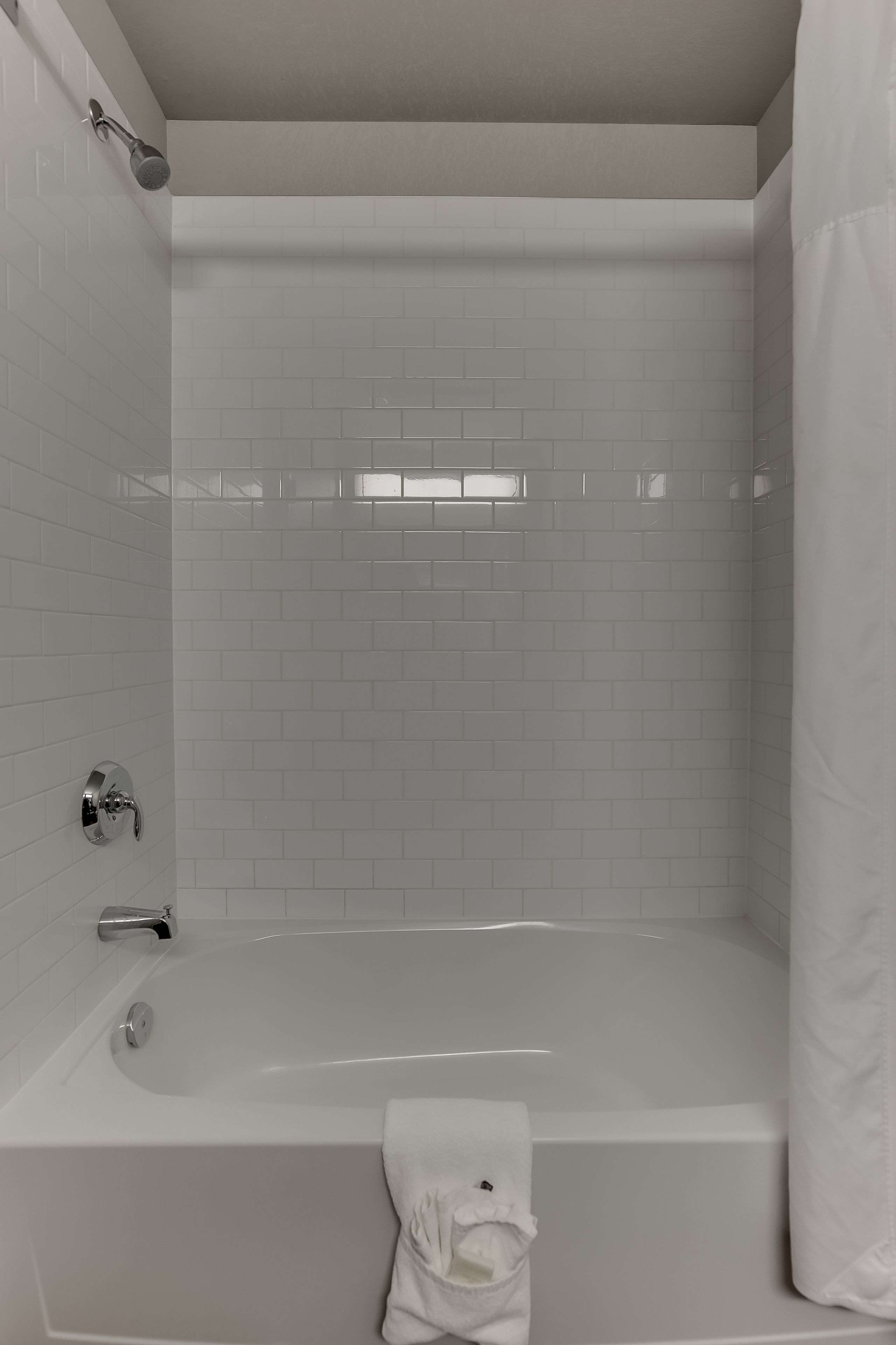 A modern bathroom with a bathtub, a showerhead, and a towel rack.