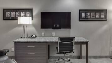 Un espacio de oficina moderno con un escritorio, una silla y un televisor de pantalla plana montado en la pared.