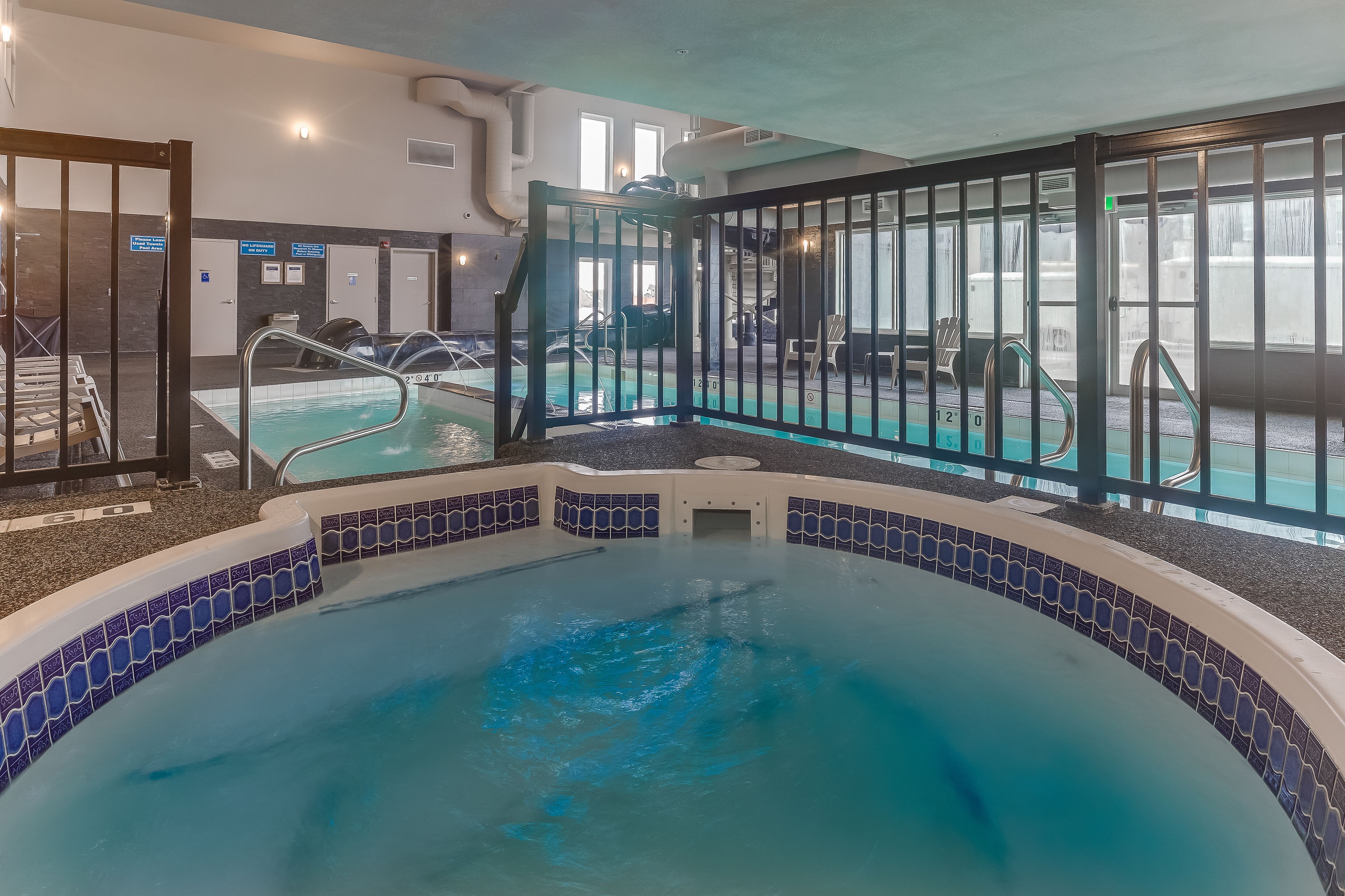 An indoor swimming pool with a tiled border, a changing room, and a door leading to another area.