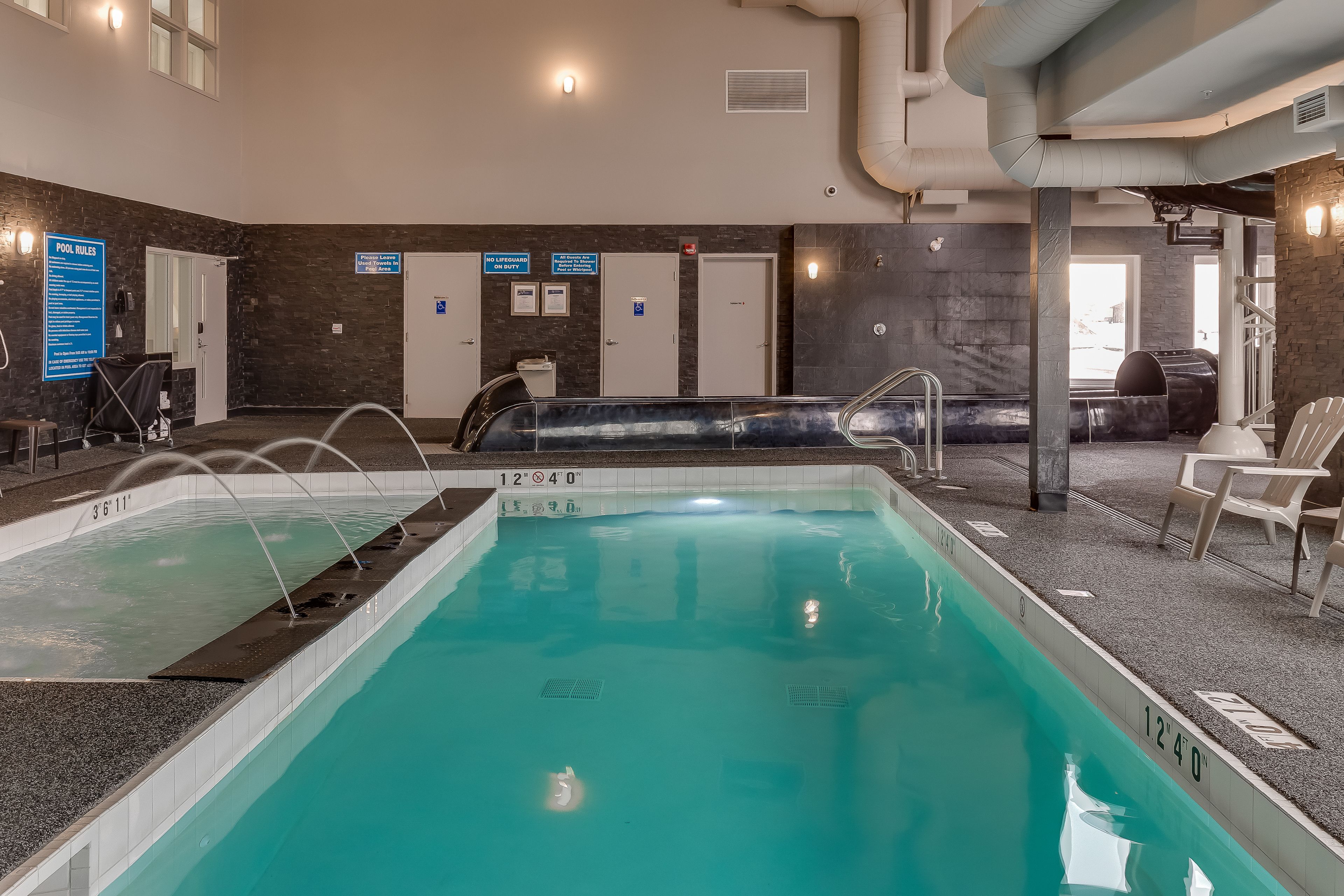 A pool area with clear water, marked depth lines, and a lifeguard chair.