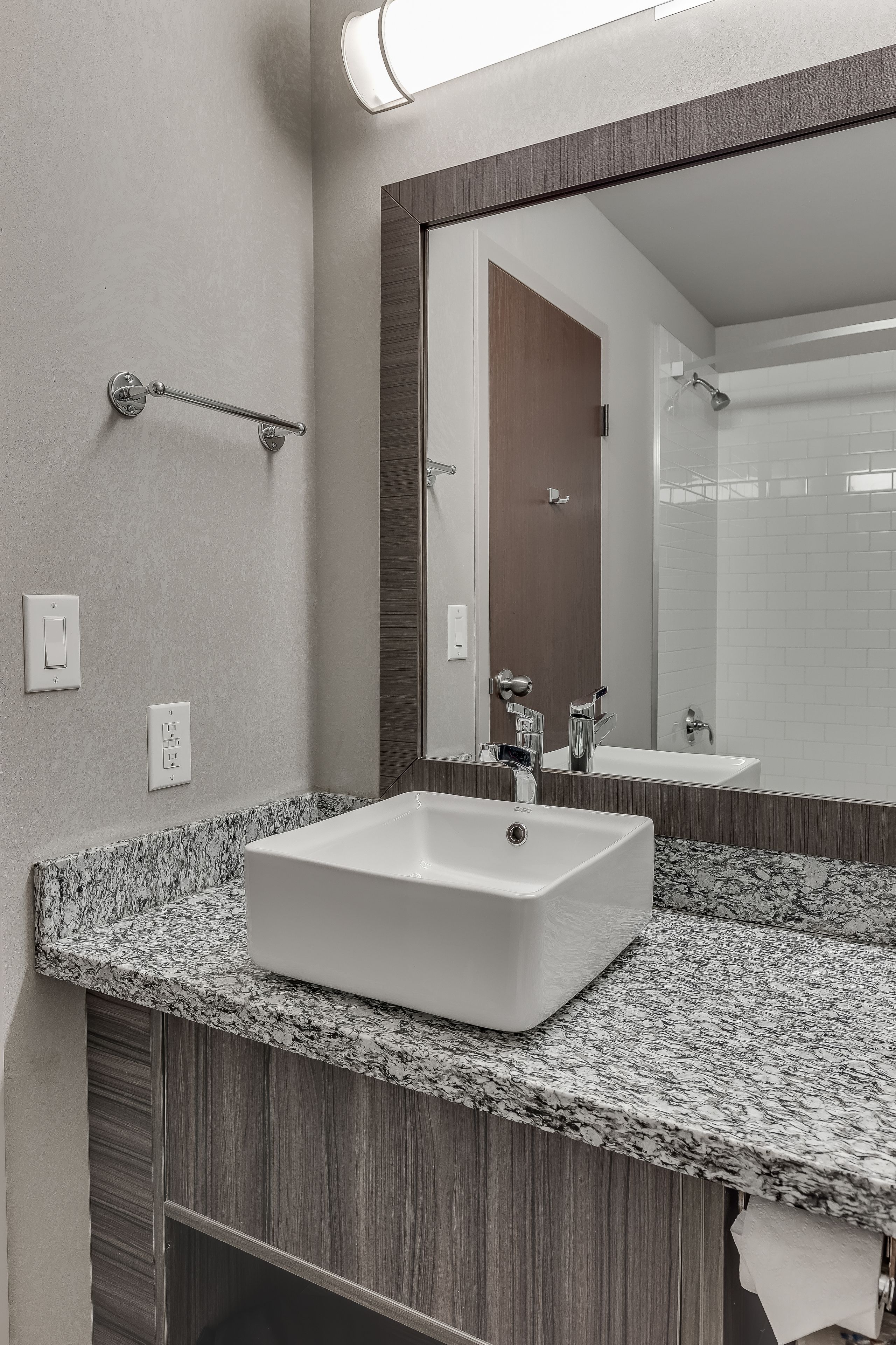A modern bathroom with a rectangular sink, a large mirror, and a towel rack.
