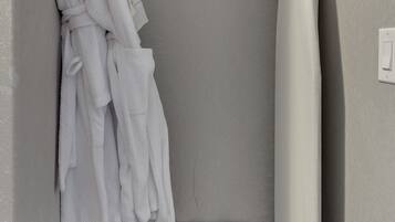 Un bagno con portasciugamani, asciugamani bianchi, tenda da doccia e una sedia a righe bianche e nere.