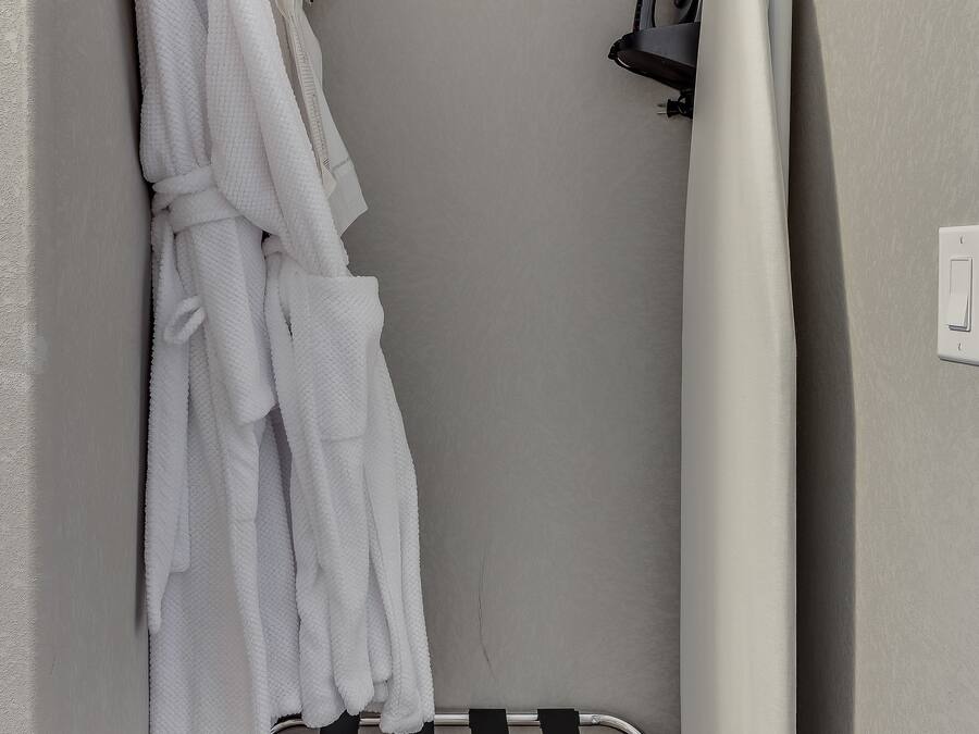 Un bagno con portasciugamani, asciugamani bianchi, tenda da doccia e una sedia a righe bianche e nere.