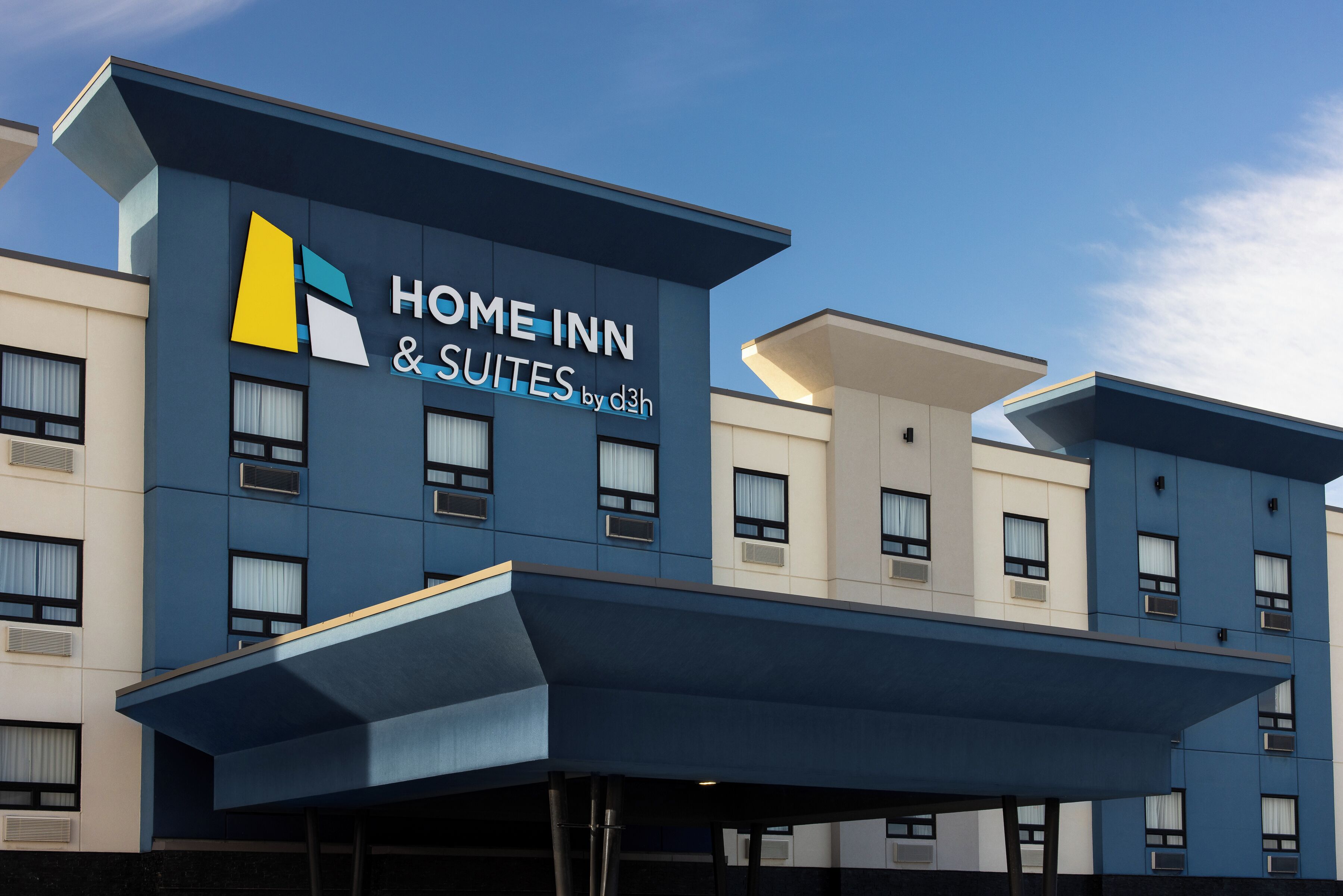 Um hotel moderno com uma placa indicando "Home Inn & Suites by d3h".