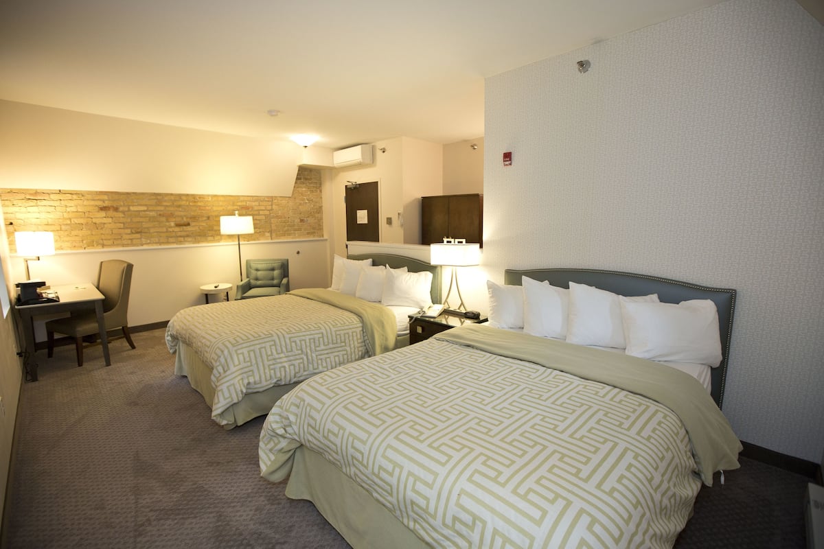 Habitación de hotel con dos camas, un escritorio y una silla.