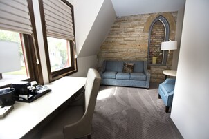 Una habitación acogedora con escritorio, sofá azul y pared de piedra.