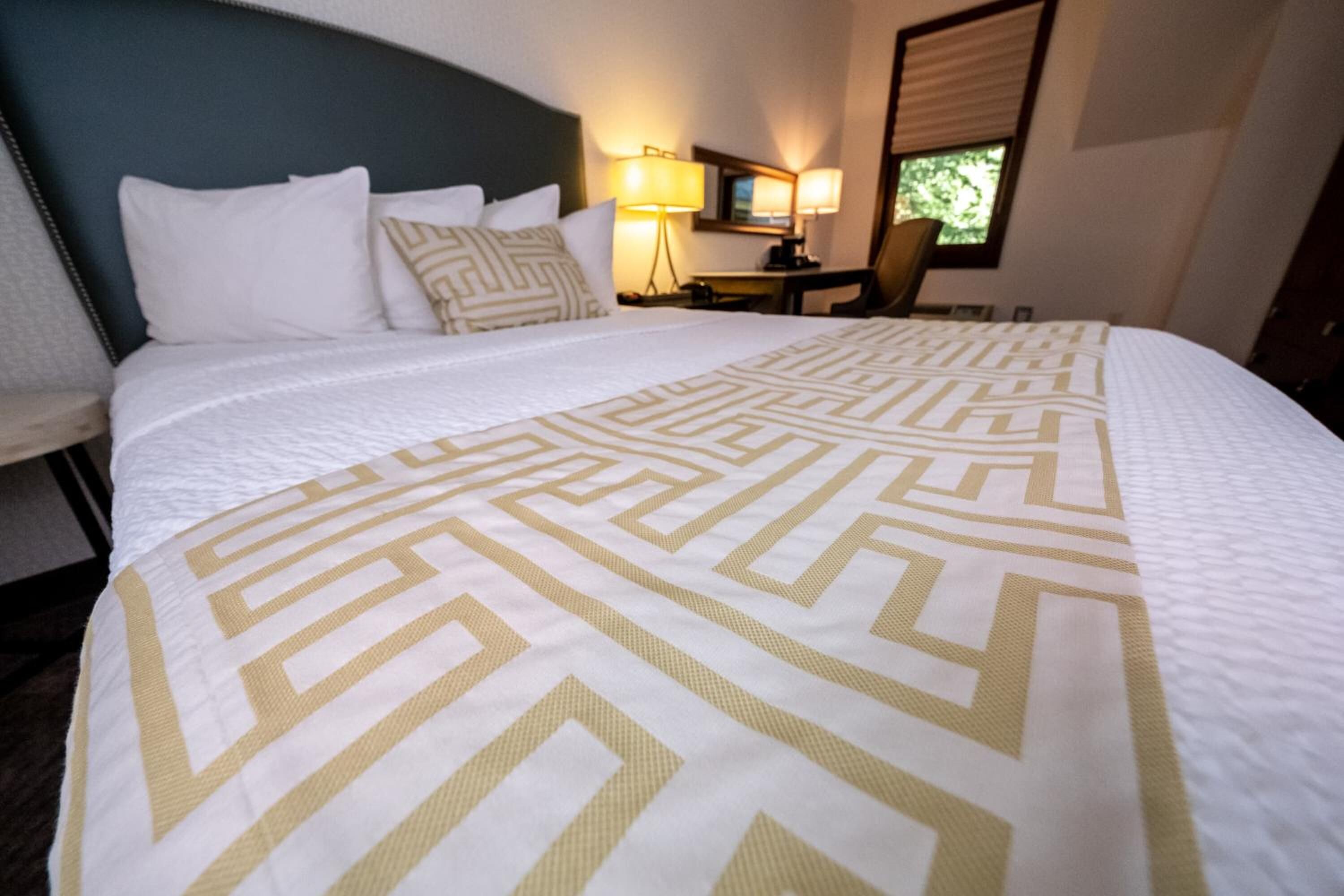 A hotel room with a large bed, a desk, and a chair.
