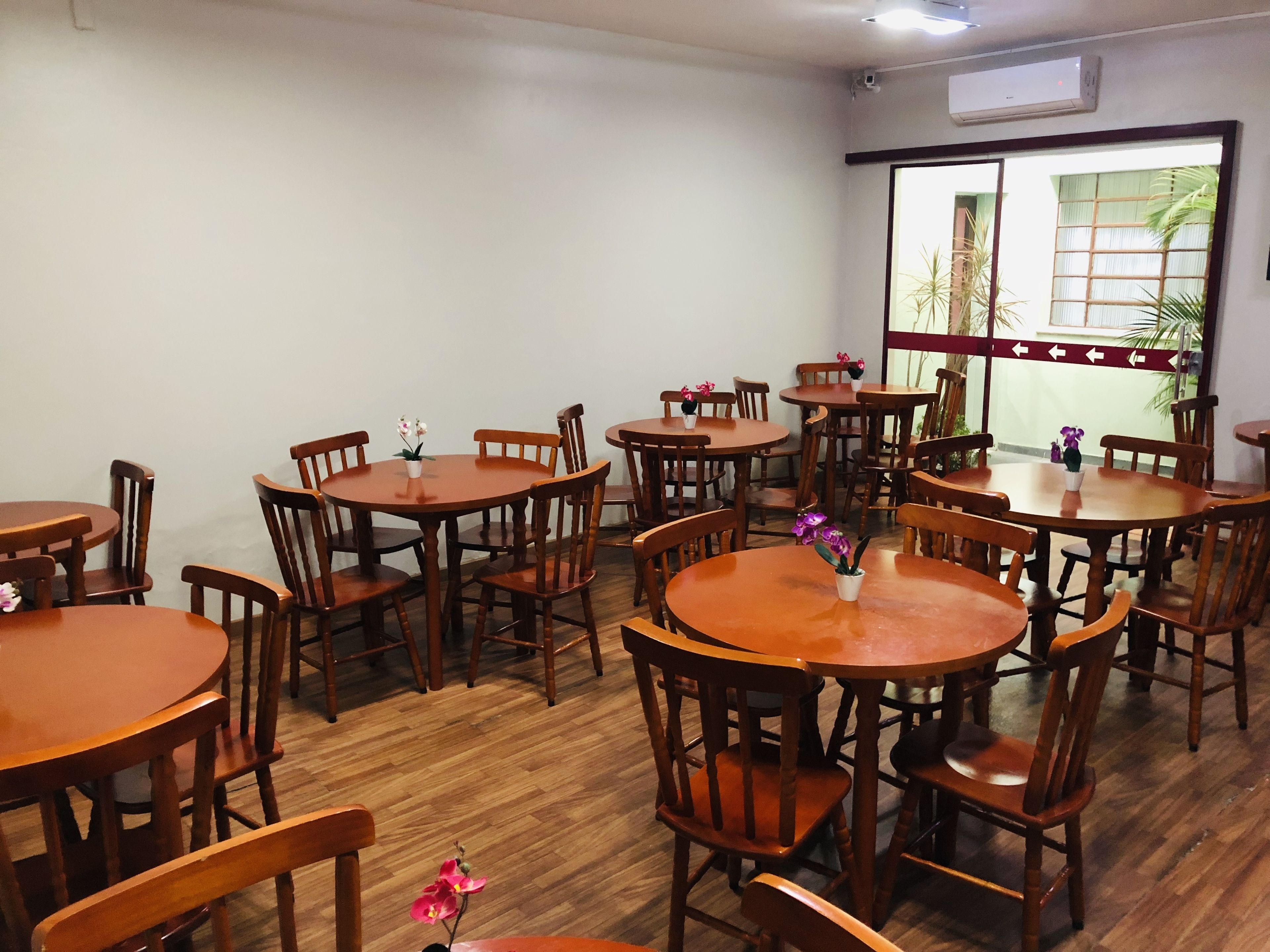 A dining area with multiple wooden tables and chairs, arranged in a spacious layout.