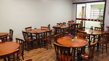 A dining area with multiple wooden tables and chairs, arranged in a spacious layout.