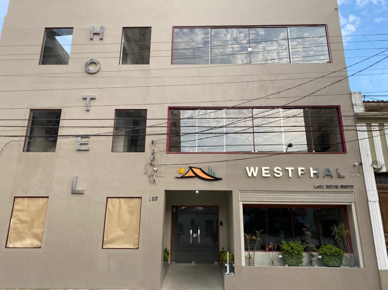 Um hotel chamado WESTPHAL com fachada moderna, grandes janelas e entrada visível.